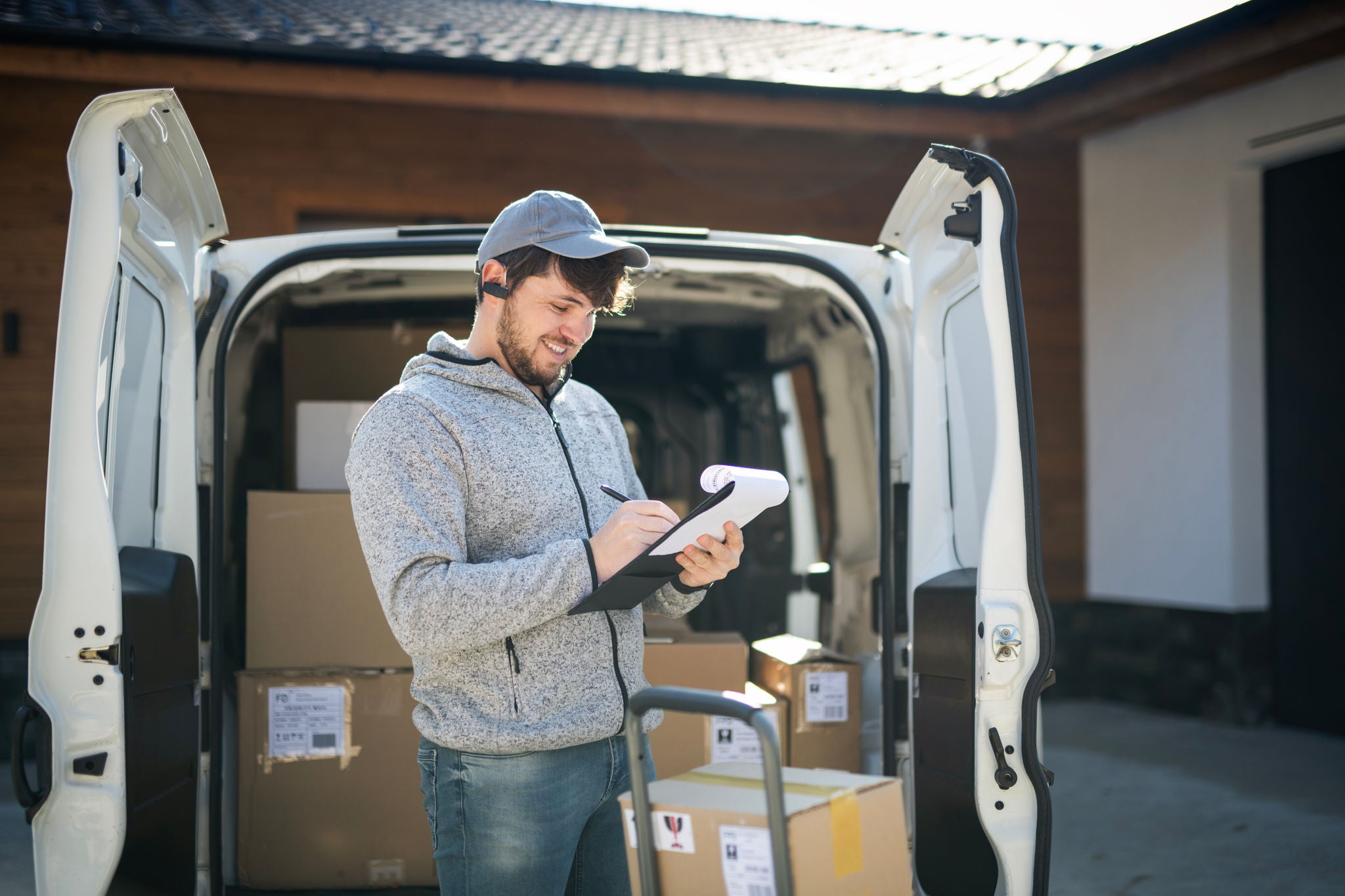 Delivery man unloading boxes from white van.He is at the address delivering parcels.