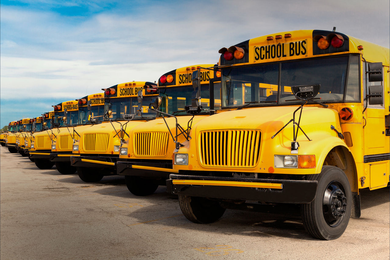 Parked fleet of yellow school buses at depot, illustrating Webasto system solutions: batteries, electric heaters and thermal-management for electrified buses.